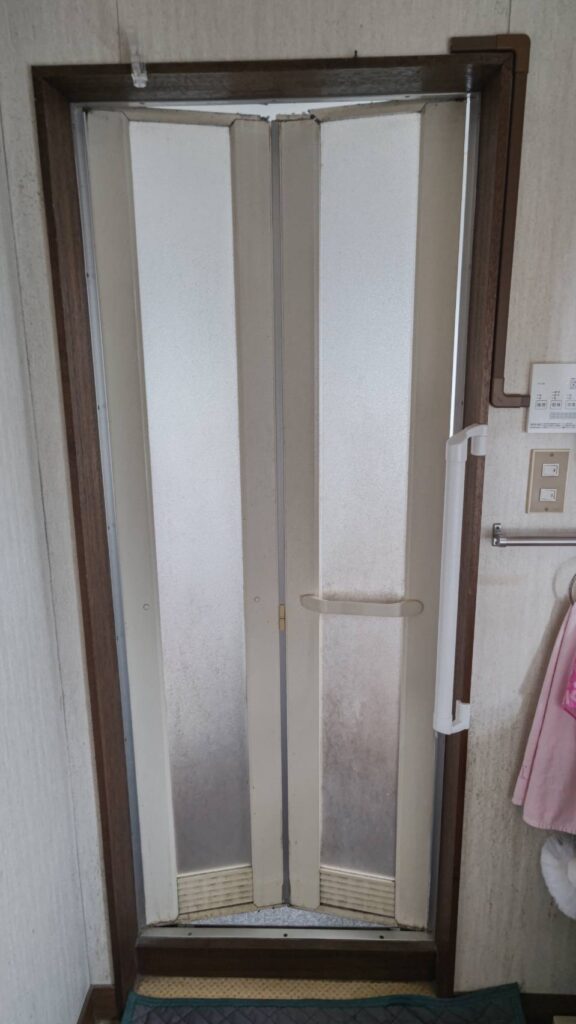 一宮市の住宅で交換前の浴室ドア。古くなり開け閉めがしづらくなった状態を撮影。