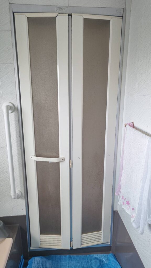 一宮市の住宅で交換前の浴室ドア。古くなり開け閉めがしづらくなった状態を撮影。